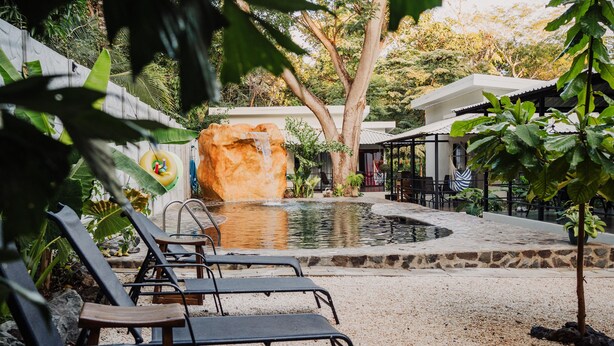 A pool area with lounge chairs, a rock feature, and a small waterfall. - Mini Oasis in Avellanas beach, natural pool, parking, A/C, kitchen #1 (Tamarindo)