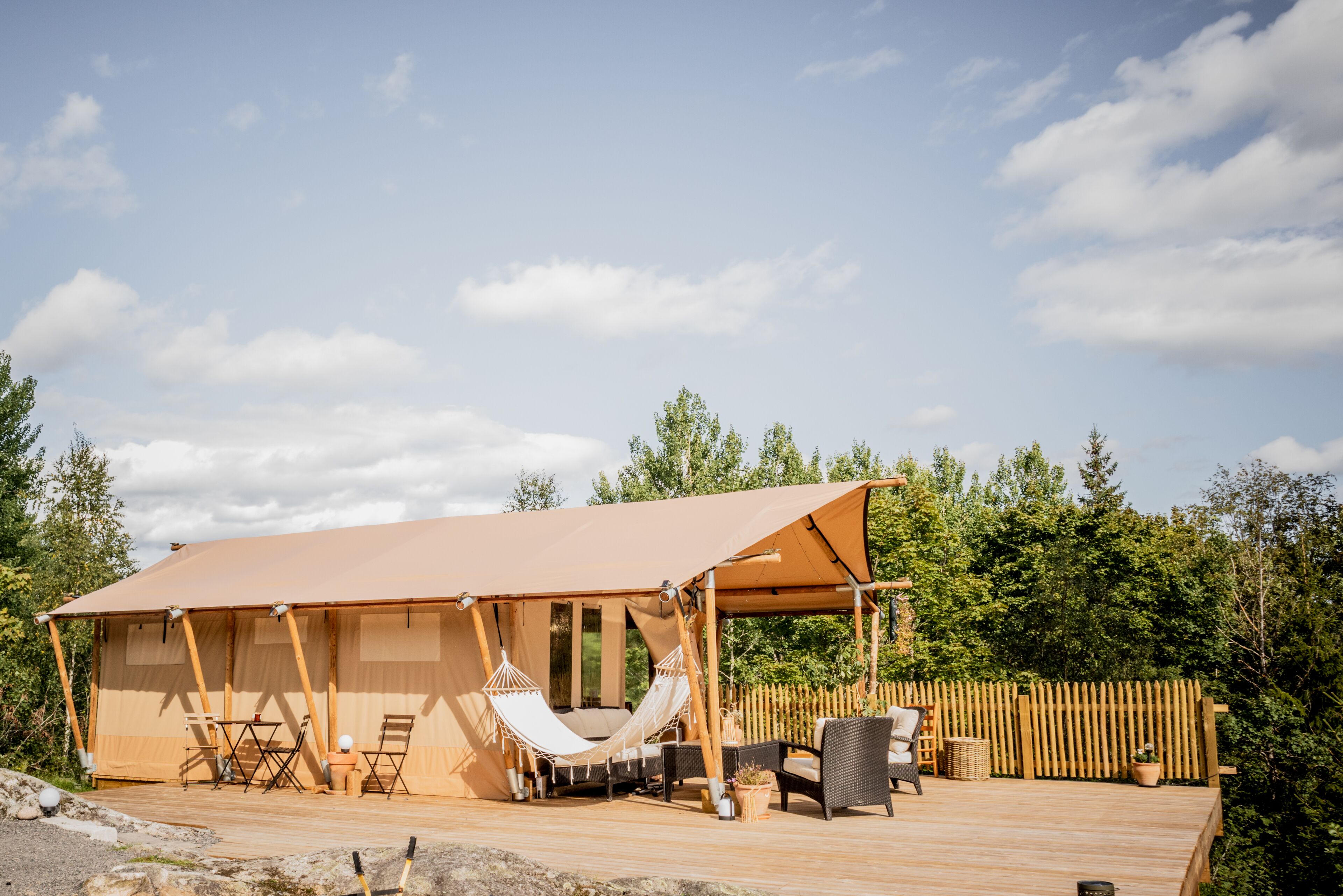 A spacious outdoor area with a large tent, hammocks, and outdoor furniture.