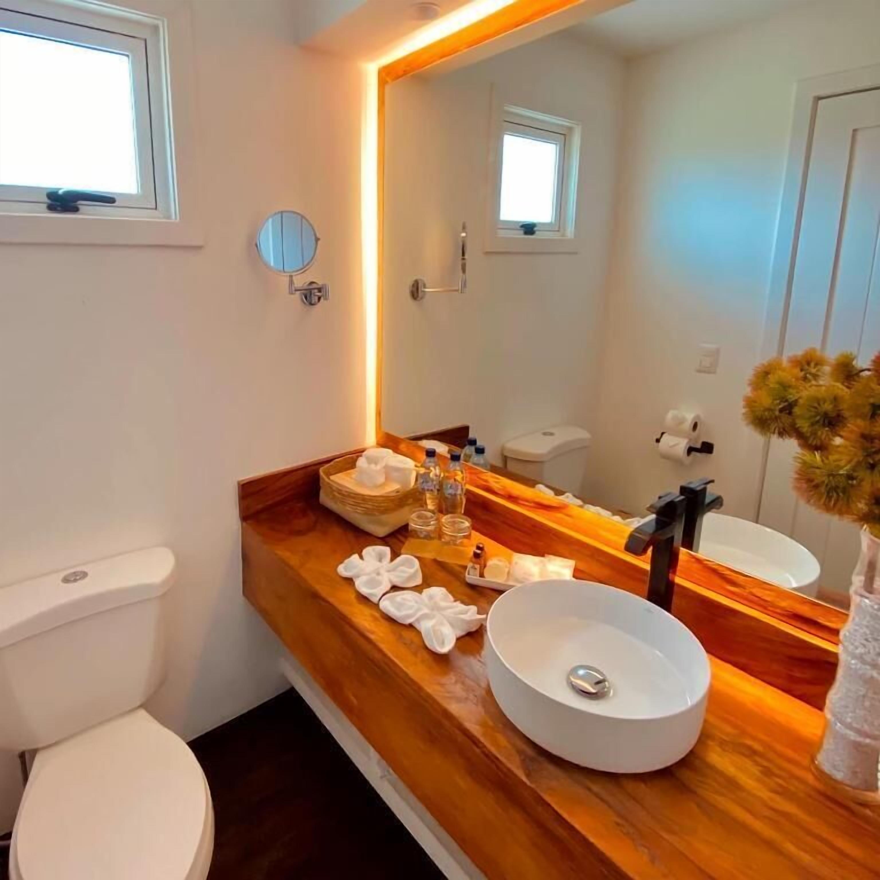A modern bathroom with a wooden vanity, a round sink, and a large mirror.