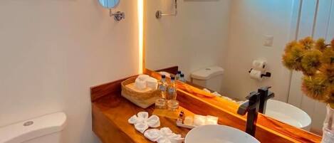 A modern bathroom with a wooden vanity, a round sink, and a large mirror.