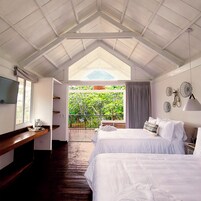 Un dormitorio con dos camas, televisión, cafetera y balcón con vistas a zonas verdes.