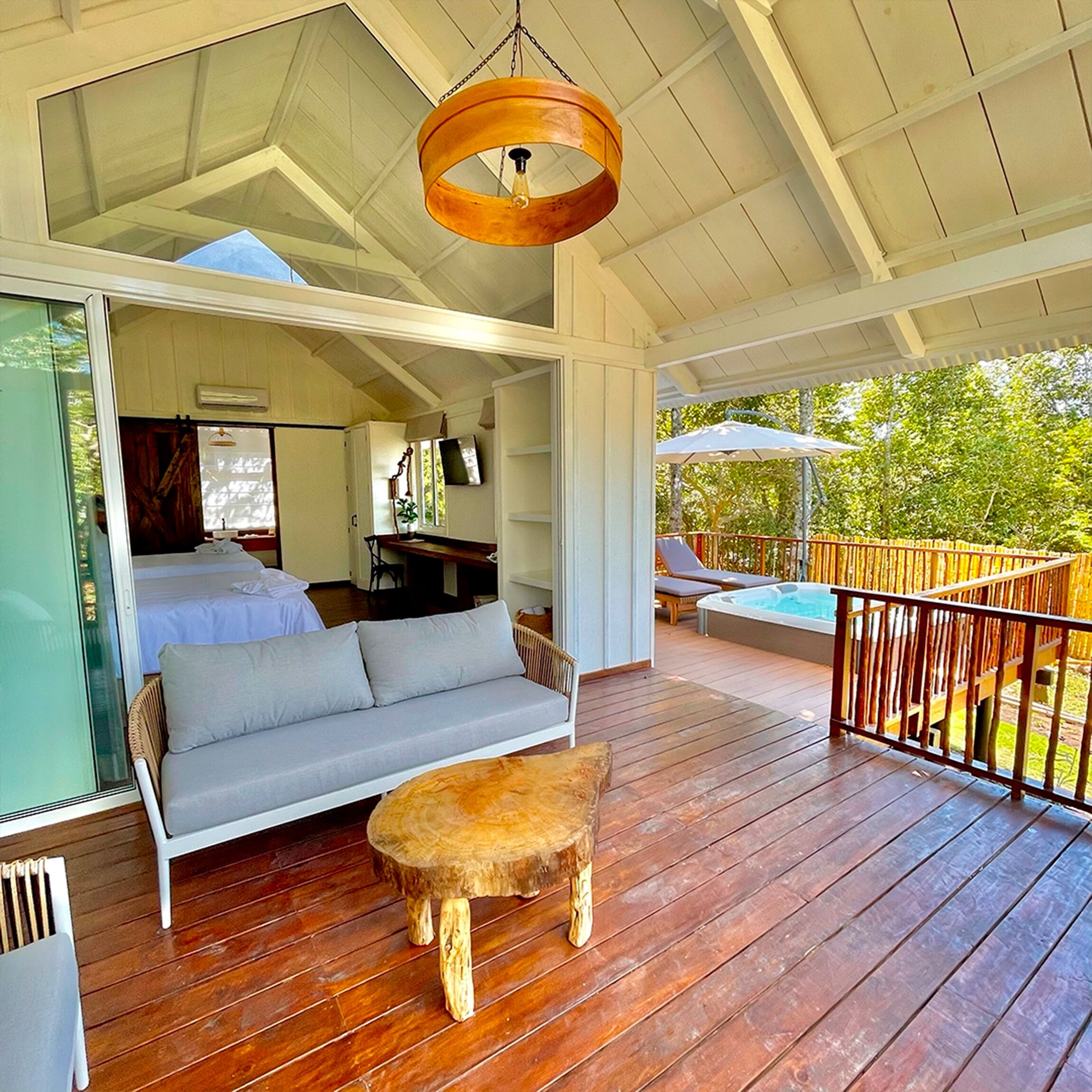 A spacious outdoor deck with a wooden table, a sofa, and a hot tub.