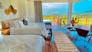 A room with two beds, a wooden floor, a balcony with a view, and a table with chairs. - Finca San Cayetano (Alotenango)