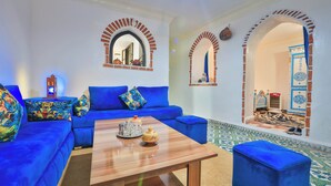 A living room with a blue sofa, a wooden coffee table, and a patterned rug.