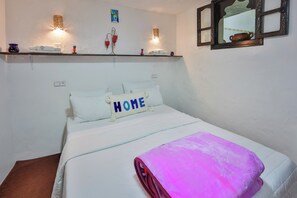 A neatly made bed with a 'HOME' pillow, a pink blanket, and a shelf with towels and a vase. - DAR LA Aicha Chefchaouen (Chefchaouen)