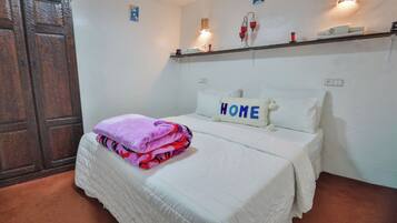 A bedroom with a bed, a wardrobe, a shelf with decorative items, and a wall-mounted light fixture.