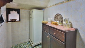 A compact kitchen with a white refrigerator, a wooden cabinet, and a patterned floor.