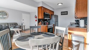 Una cocina moderna con armarios de madera, un microondas y un refrigerador. Hay un comedor con una mesa redonda y sillas.