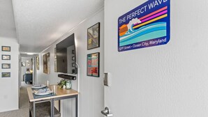 Um corredor com área de jantar, obras de arte nas paredes e uma placa indicando a localização como 121st Street, Ocean City, Maryland.