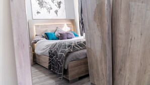 A bedroom with a bed, a world map artwork, and a wooden headboard. - Stunning 2-bed Apartment in Tipton Sleeps 3 (Tipton)