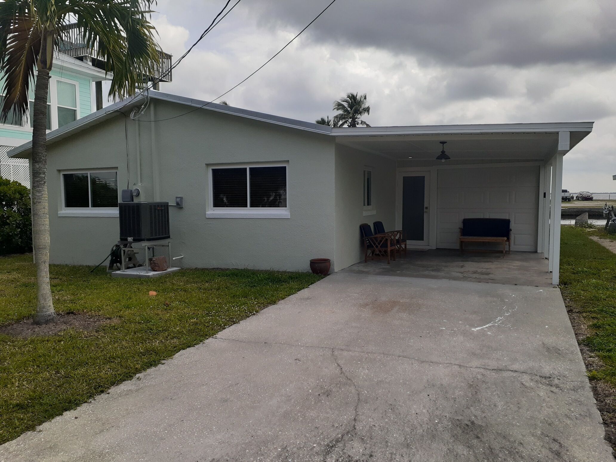 A single-story house with a covered porch, a small patio, and a visible air conditioning unit.