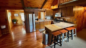 Eine geräumige Küche mit Holzausbau, einem Edelstahlkühlschrank und einer Arbeitsplatte aus Granit.