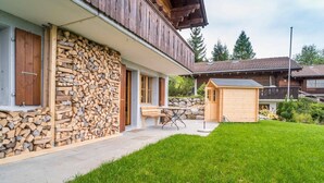 A modern house with a stone wall, a wooden deck, and a small wooden shed.