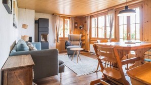 A cozy cabin interior with a sofa, a dining table, and a fireplace.