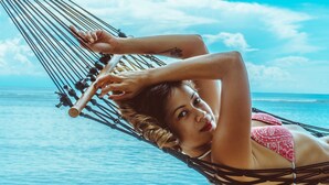 Una persona recostada en una hamaca en la playa, con el océano al fondo.