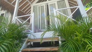 Una construcción con techo de paja y una escalera de madera que conduce a una puerta de cristal.