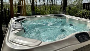 A hot tub outdoors with a wooden pergola nearby.
