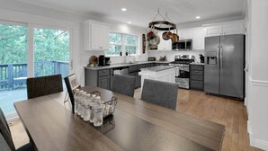 A modern kitchen with white cabinets, stainless steel appliances, and a dining area with a wooden table and chairs.