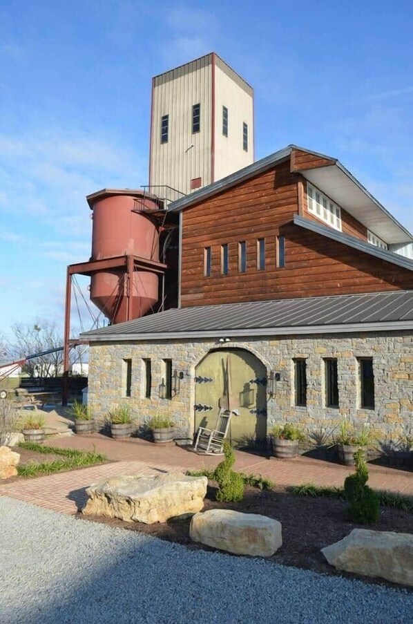 A building with a stone facade, a large silo, and a wooden structure.