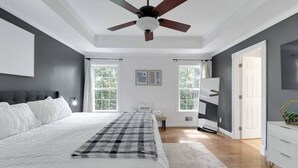 A bedroom with a bed, a ceiling fan, a dresser, and a window.