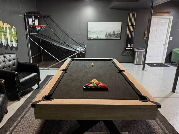 A pool table with balls, a leather sofa, a framed picture, and a door.