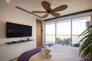 A hotel room with a large bed, a television, a ceiling fan, and a balcony with a view. - U-GO Edificio H2 (Cartagena)
