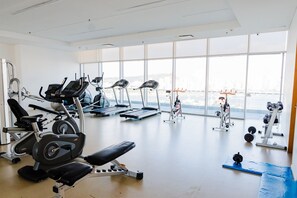 A gym with cardio machines, weightlifting equipment, and a bench. - U-GO Edificio H2 (Cartagena)