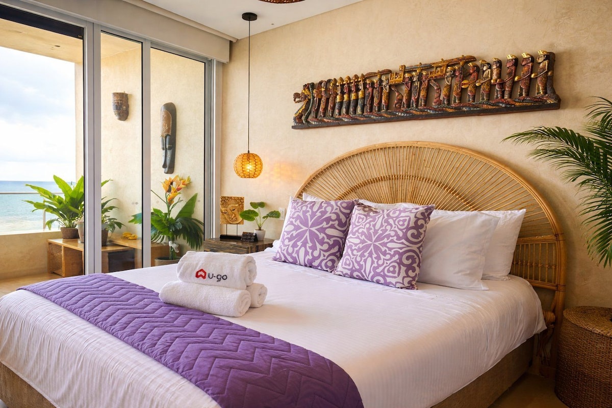 Hotelkamer met een bed, groot raam, een kunstwerk aan de muur en een balkon met planten.