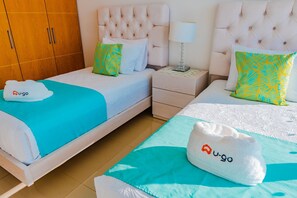 Ein Hotelzimmer mit zwei Betten, einem Kleiderschrank, einem Nachttisch und einer Lampe.