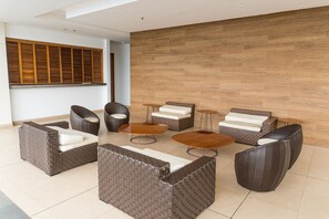 A modern lounge area with wicker furniture, a wooden wall, and a large window.