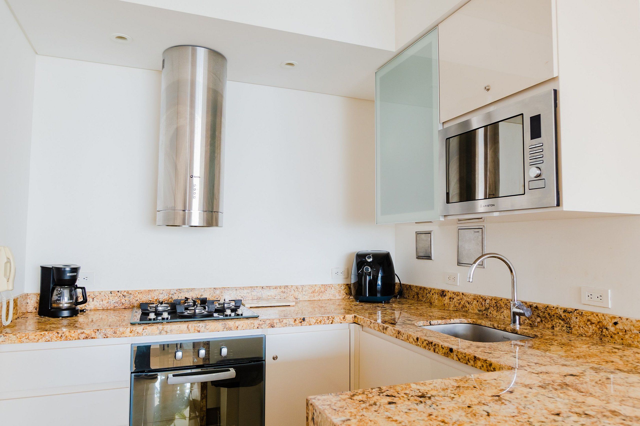A modern kitchen with stainless steel appliances, a granite countertop, and white cabinetry.