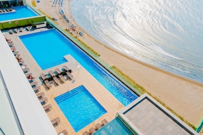 Uma área de piscina no terraço com várias piscinas e vista para a praia.