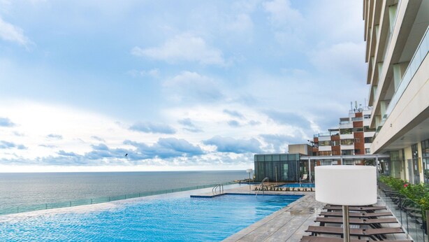 Une piscine avec vue sur la mer, des chaises longues et un bâtiment moderne.