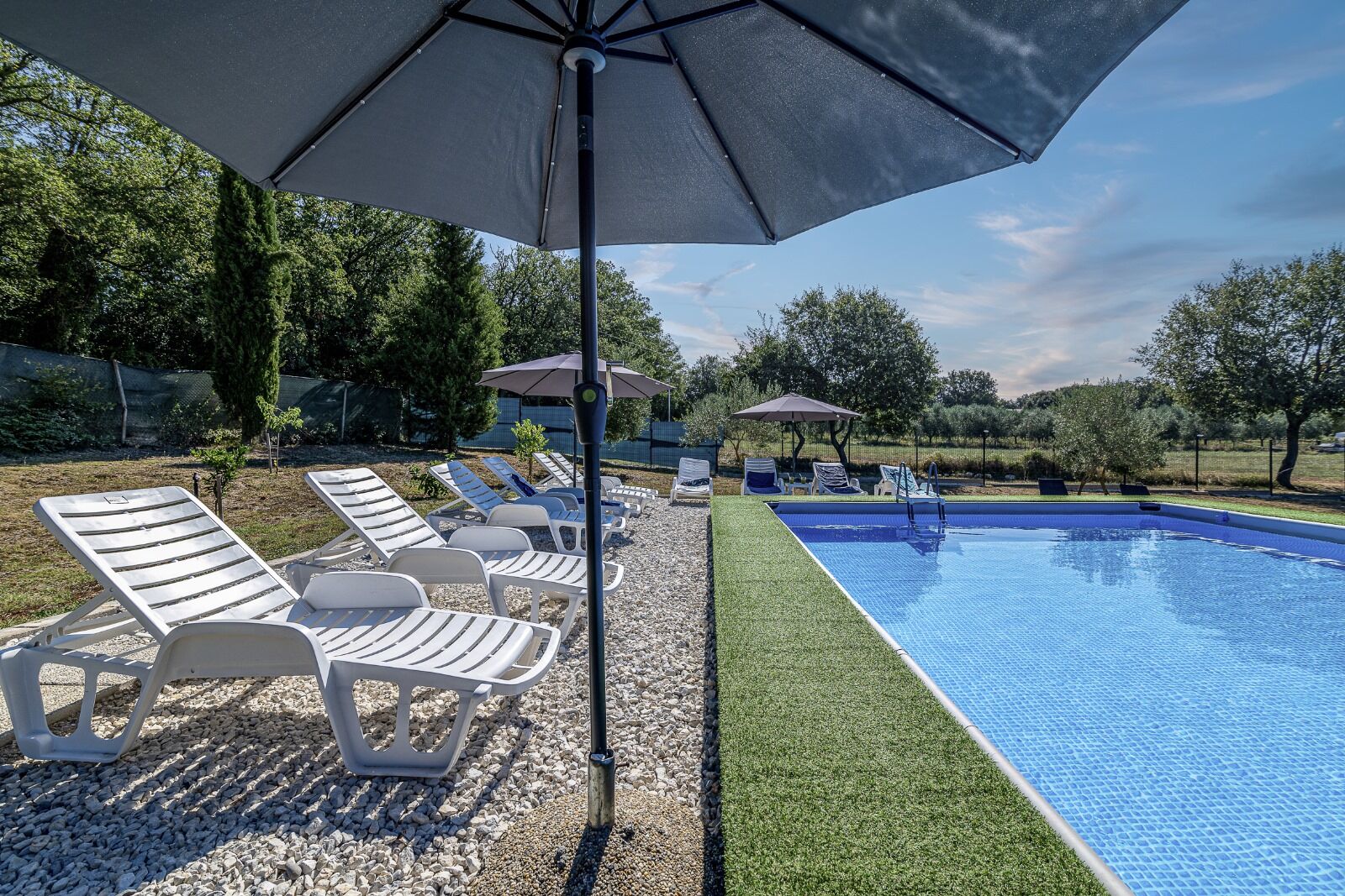 Ein Schwimmbecken mit Liegestühlen und Sonnenschirmen.