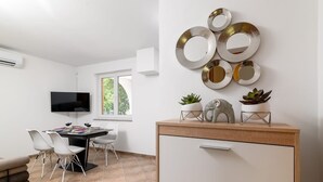 Eine moderne Küche mit Essbereich, einem an der Wand befestigten Fernseher und einem Fenster, das natürliches Licht hereinlässt.