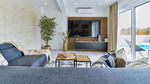 A modern living room with a sofa, a coffee table, and a TV area with a wooden panel design. - Holiday Home in Bibinje with Seaview, Balcony, Air condition, WIFI (5201-1) (Bibinje)