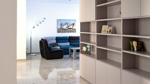 A modern living room with a grey sofa, a coffee table, and a bookshelf. - Seaside Serenity - Luxe Penthouse - near the beach (Il-Mellieha)