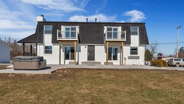 Ein zweistöckiges Haus mit Veranda, überdachter Terrasse und Auffahrt.