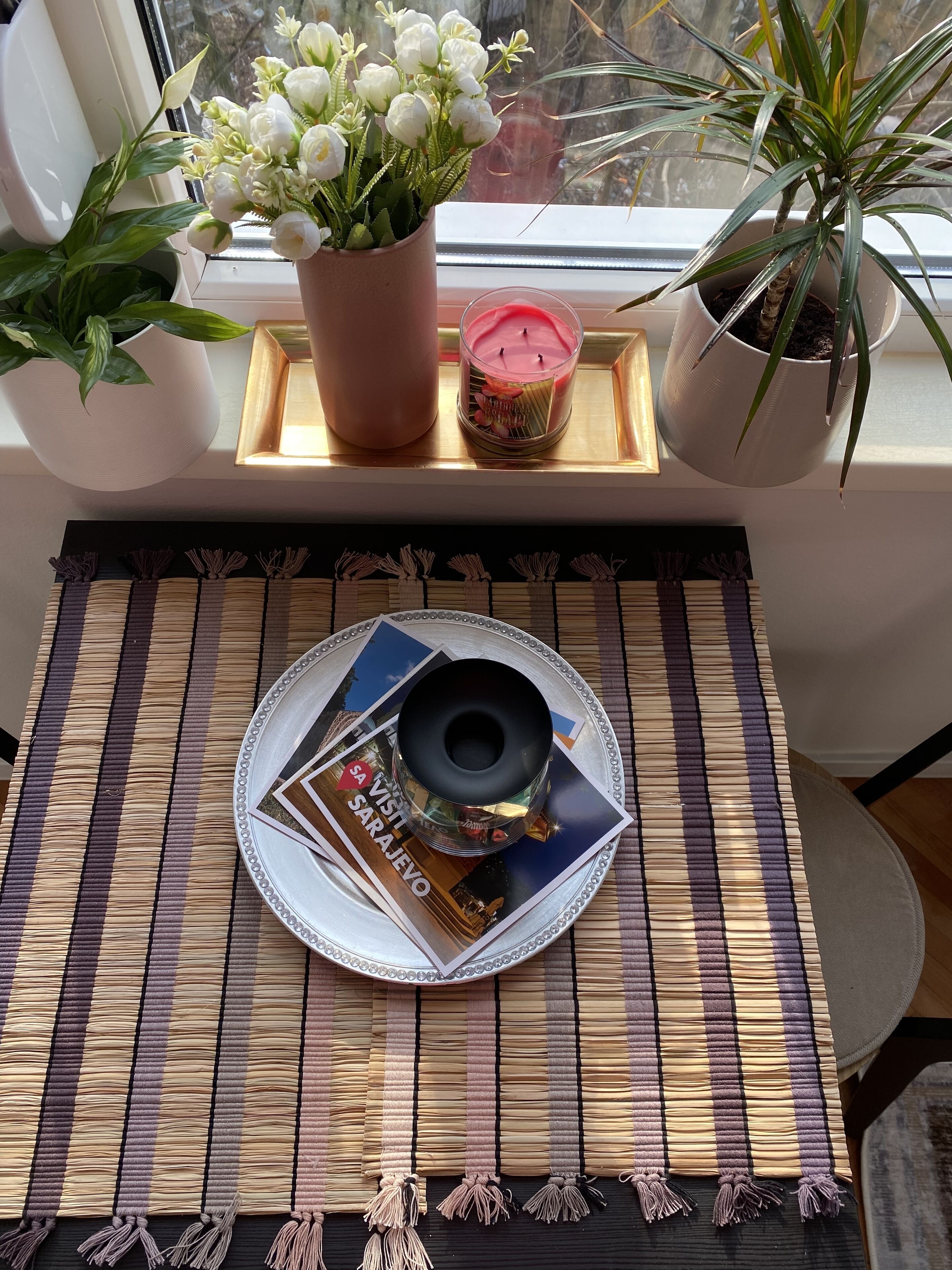 Una mesa con un plato decorativo, una vela y una planta en maceta.
