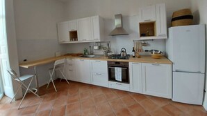 A compact kitchen with white cabinets, a gas stove, a sink, and a refrigerator. - Carmine's Balcony (Napoli)