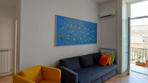 A living room with a blue sofa, a yellow armchair, and a blue abstract painting on the wall. - Carmine's Balcony (Napoli)