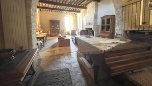 Una habitación histórica con suelo de piedra, mobiliario de madera y techo abovedado.