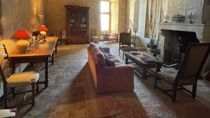 Una habitación rústica con vigas de madera a la vista, una chimenea de piedra, una mesa de madera con sillas y un sofá.