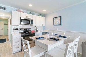 A modern kitchen with white cabinets, a stainless steel microwave, and a gas stove.