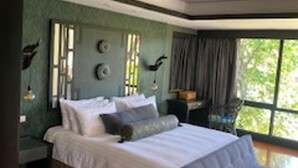 A bedroom with a large bed, a side table, a nightstand, and a window with curtains. - Poolside Luxury Laguna 2-bed Villa in Cherngtalay (Choeng Thale)