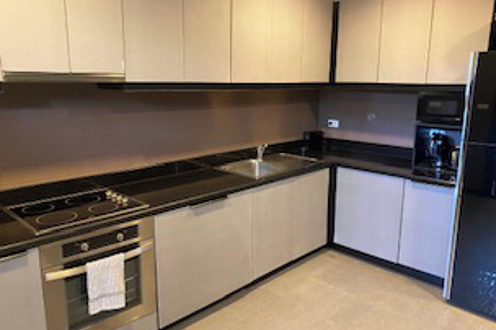 Una cocina moderna con electrodomésticos de acero inoxidable, un lavamanos y armarios de tonos claros.