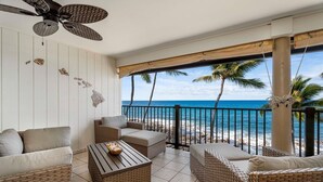 Ein Balkon mit Korbmöbeln, einem Deckenventilator und Blick auf den Ozean.