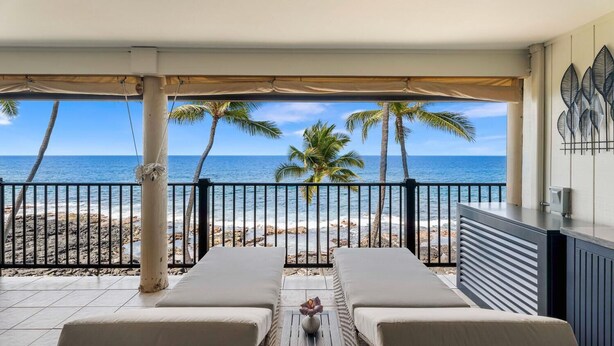 Ein Balkon mit zwei Liegestühlen, einem kleinen Tisch und Blick auf den Strand und das Meer.