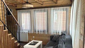 A cozy cabin interior with a wooden staircase, a cushioned sofa, and a dining table. - Zagrad Homes in Zabljak (Razvršje)