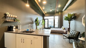 Una cocina moderna con una isla central, zona de comedor con sofá y sillas, y un ventanal que proporciona luz natural.
